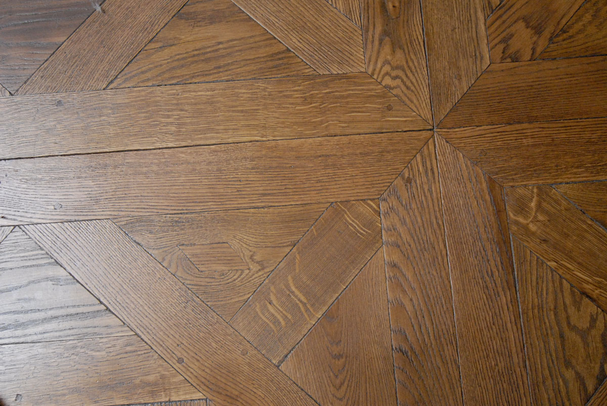 On aperÃ§oit une piÃ¨ce qui vient Ã©liminer un dÃ©faut et participer Ã  l'aspect ancien du parquet.